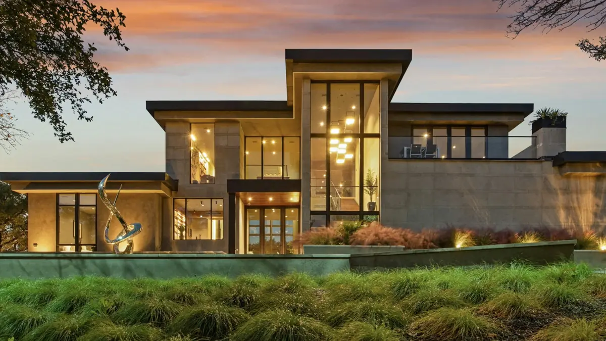 Modern custom home with large windows glowing at dusk