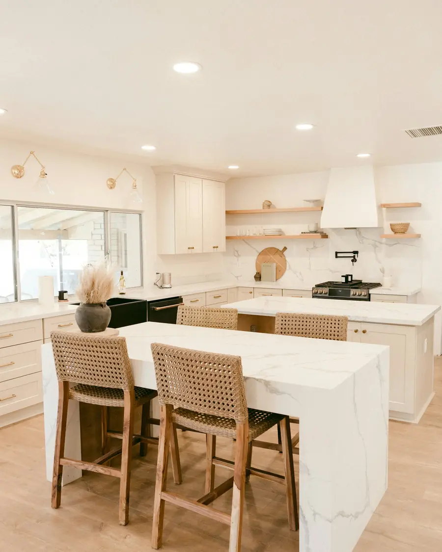Bright kitchen with marble island and woven bar stools